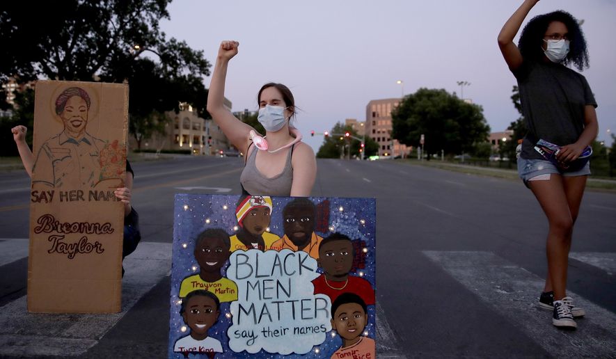 People raise their fists Tuesday, June 23, 2020 in Kansas City, Mo., as they protest the death of Black people, including Breonna Taylor, at the hands of police (AP Photo/Charlie Riedel)