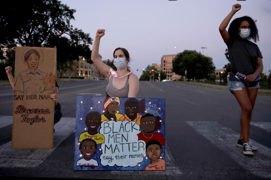 People raise their fists Tuesday, June 23, 2020 in Kansas City, Mo., as they protest the death of Black people, including Breonna Taylor, at the hands of police (AP Photo/Charlie Riedel)