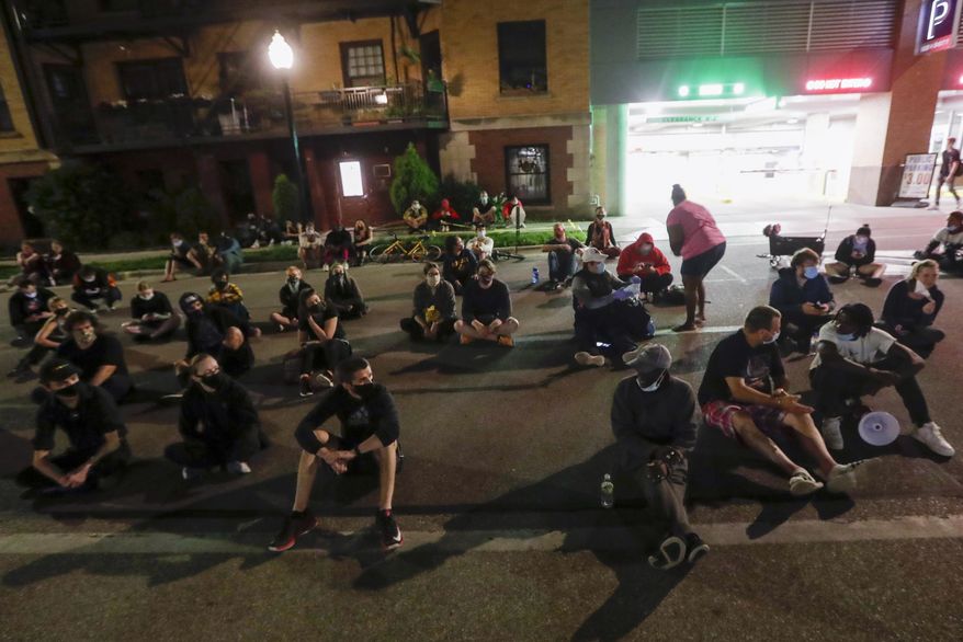 Protesters sit on the street outside the Dane County Jail on Wednesday, June 24, 2020, in Madison, Wis. About 40 people gathered outside the jail, calling for the release of a Black man who was arrested Tuesday after shouting at restaurant customers through a megaphone while carrying a baseball bat. (AP Photo/Morry Gash)