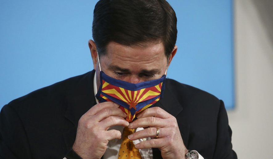 Arizona Republican Gov. Doug Ducey puts a face-covering back on after speaking about the latest coronavirus data at a news conference Thursday, June 25, 2020, in Phoenix. (AP Photo/Ross D. Franklin, Pool)