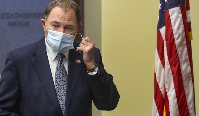 Utah Gov. Gary Herbert takes off his mask before speaking during the daily briefing on the state's efforts to fight COVID-19 Wednesday, June 24, 2020, in Salt Lake City. Hebert said he will require face masks at state-run buildings that include liquor stores and higher education offices and approve a request from the state's largest county to make face coverings required in certain situations. But the Republican governor stopped short of implementing a statewide requirement for face coverings as several other states have done such as Washington, California and New York. (Steve Griffin/ Deseret News via AP, Pool)