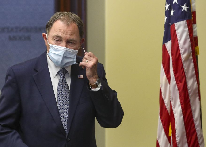 Utah Gov. Gary Herbert takes off his mask before speaking during the daily briefing on the state's efforts to fight COVID-19 Wednesday, June 24, 2020, in Salt Lake City. Hebert said he will require face masks at state-run buildings that include liquor stores and higher education offices and approve a request from the state's largest county to make face coverings required in certain situations. But the Republican governor stopped short of implementing a statewide requirement for face coverings as several other states have done such as Washington, California and New York. (Steve Griffin/ Deseret News via AP, Pool)