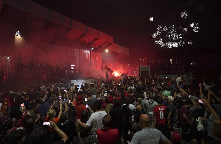 Liverpool supporters celebrate as they gather outside of Anfield Stadium in Liverpool, England, Thursday, June 25, 2020 after Liverpool clinched the English Premier League title. Liverpool took the title after Manchester City failed to beat Chelsea on Wednesday evening. (AP photo/Jon Super)