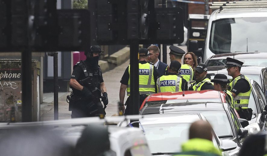 Armed police at the scene of an incident in Glasgow, Scotland, Friday June 26, 2020. Scottish police say the individual shot by armed police during an incident in Glasgow has died and that six other people including a police officer are in hospital being treated for their injuries.  (Andrew Milligan/PA via AP)
