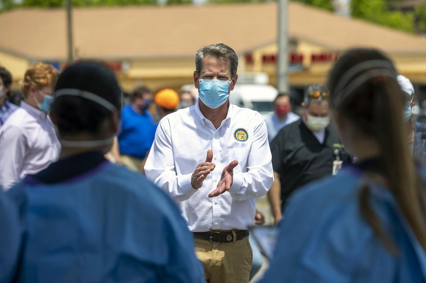 Georgia Governor Brian Kemp applauds healthcare workers for their service while touring a community COVID-19 testing site in the parking lot of La Flor de Jalisco #2 during a visit to Gainesville, Ga., Friday, May 15, 2020. (Alyssa Pointer/Atlanta Journal-Constitution via AP)