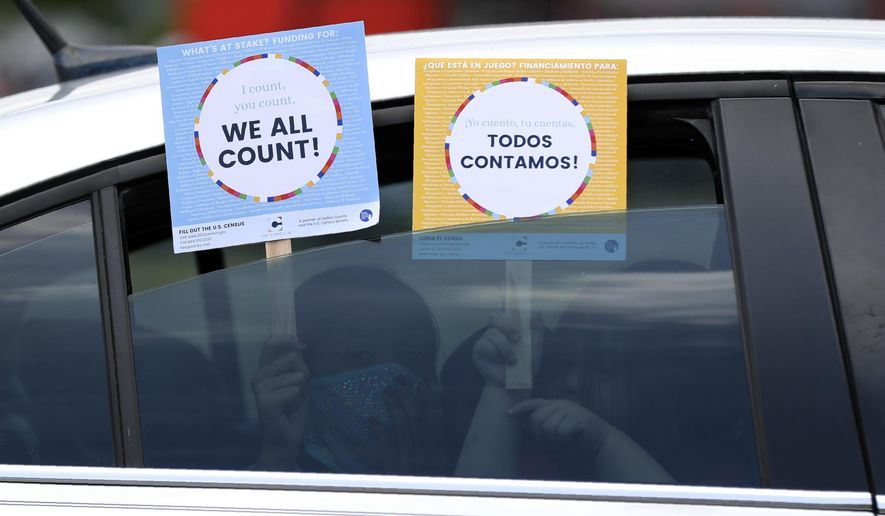 Two young children hold signs through the car window that make reference to the 2020 U.S. Census as they wait in the car with their family at an outreach event in Dallas, Thursday, June 25, 2020. In a collaborative effort, the nonprofit group, The Concilio, partnered with the North Texas Food Bank, Catholic Charities Dallas and Bachman Lake Together, to hold the event where area residents were encouraged to report their family numbers to the U.S. Census. The outreach event was held in the Bachman Lake community which historically is one of many undercounted neighborhoods in Dallas County according to The Concilio. Due to COVID-19, the Census self-respond date online, by phone or mail has been extended to Oct. 31. (AP Photo/Tony Gutierrez)