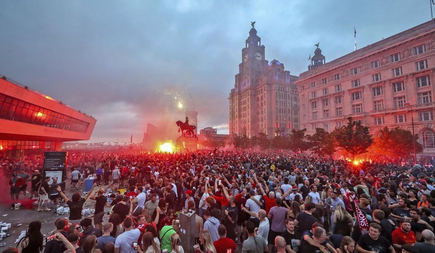Liverpool fans let off flares outside the Liver Building in Liverpool, Friday June 26, 2020, as Liverpool soccer fans gather and celebrate for the team clinched the English Premier League title. (Peter Byrne/PA via AP)