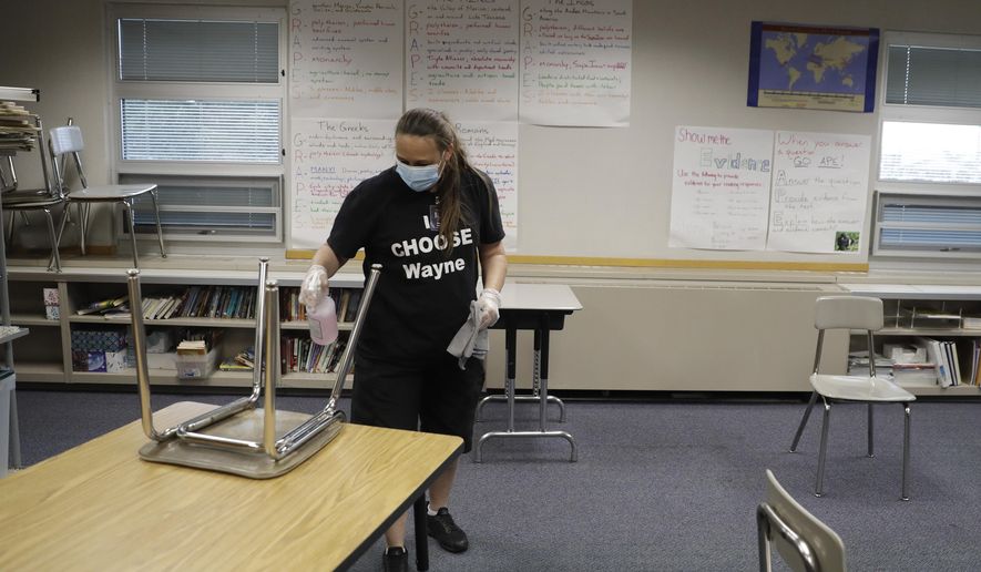 Diane Tomey cleans a classroom at McClelland Elementary School, Monday, June 22, 2020, in Indianapolis. As the coronavirus pandemic continues to unfold, Indiana schools are making plans for students to return to classes as early as late July, but with questions remaining about how instruction will happen -- whether online, in person, or a mix of both -- some parents say they won't send their kindergartners to school this fall. (AP Photo/Darron Cummings)