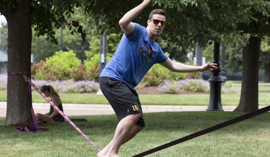 Frankie Colavito works out on a balance line in Piers Park, Saturday, June 27, 2020, in Boston. (AP Photo/Michael Dwyer)
