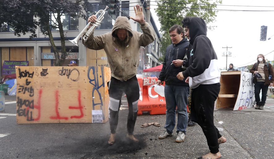Protesters dance across hot coals spread in the street in front of a closed Seattle police precinct Sunday morning, June 28, 2020, in Seattle, where several streets are blocked off in what has been named the Capitol Hill Occupied Protest zone. Seattle Mayor Jenny Durkan met with demonstrators Friday after some lay in the street or sat on barricades to thwart the city&#39;s effort to dismantle the protest zone that has drawn scorn from President Donald Trump and a lawsuit from nearby businesses. (AP Photo/Elaine Thompson) **FILE**