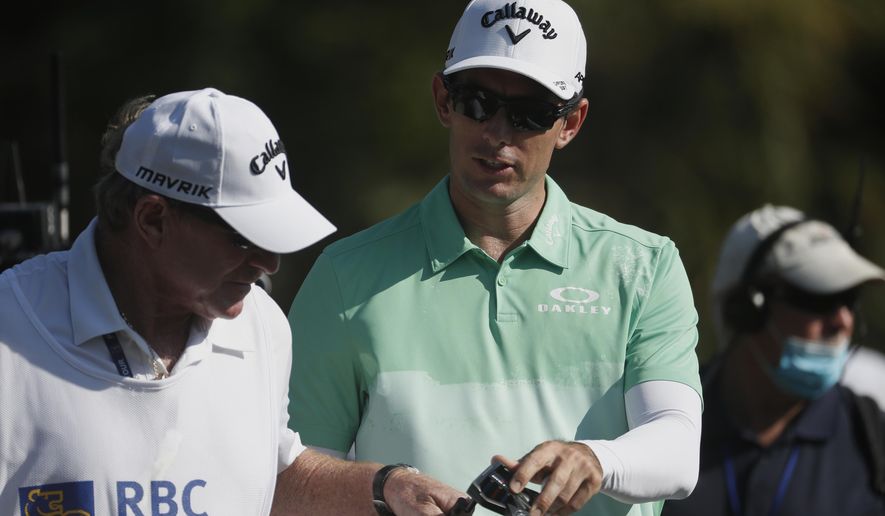 Dylan Frittelli, right, of South Africa, confers with his caddie on the 17th hole during the first round of the RBC Heritage golf tournament Thursday, June 18, 2020, in Hilton Head Island, S.C. (AP Photo/Gerry Broome)