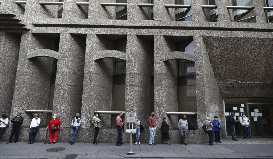 Bank customers keep their distance to help curb the spread of the new coronavirus, as they stand in line outside a bank in Mexico City, Monday, June 29, 2020. Mexico City is moving this week to the next stage of its gradual reopening from its COVID-19 pandemic lockdown. (AP Photo/Eduardo Verdugo)