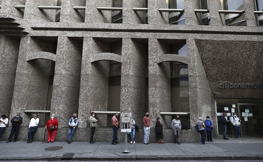 Bank customers keep their distance to help curb the spread of the new coronavirus, as they stand in line outside a bank in Mexico City, Monday, June 29, 2020. Mexico City is moving this week to the next stage of its gradual reopening from its COVID-19 pandemic lockdown. (AP Photo/Eduardo Verdugo)