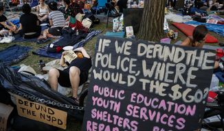 Protesters occupy an encampment outside City Hall beside signs calling for the defunding of police, Friday, June 26, 2020, in New York. (AP Photo/John Minchillo)