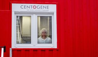 An employee of Centogene looks out of a laboratory container at the airport in Frankfurt, Germany, Monday, June 29, 2020. In the future, people will be able to be tested for the corona virus within a few hours at Germany&#39;s first &amp;quot;Airport Corona Test&amp;quot; centre. (AP Photo/Michael Probst)