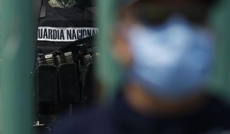 A member of the National Guard stands watch inside the gates as state police guard the street outside, at Las Americas General Hospital in Ecatepec, a suburb of Mexico City, Wednesday, May 20, 2020. Mexico City, one of the world&#39;s largest cities and the epicenter of the country&#39;s coronavirus epidemic, will begin a gradual reopening June 1, its mayor said Wednesday, even as daily new infections continued to set records. (AP Photo/Rebecca Blackwell)