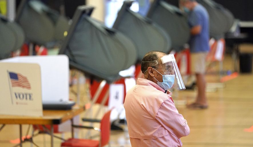 Harris County election clerk Jose Mendoza watches over voting booths, Monday, June 29, 2020, in Houston. Early voting for the Texas primary runoffs began Monday. (AP Photo/David J. Phillip)