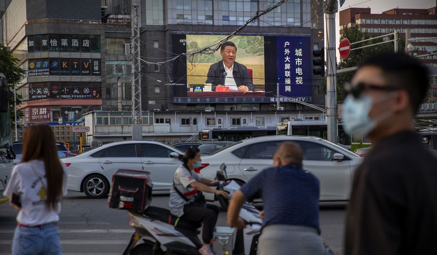 People wearing face masks to protect against the new coronavirus wait to cross an intersection as a large video screen shows Chinese President Xi Jinping speaking in Beijing, Tuesday, June 30, 2020. China approved a contentious national security law that will allow authorities to crack down on subversive and secessionist activity in Hong Kong, a move many see as Beijing&#x27;s boldest yet to erase the legal firewall between the semi-autonomous territory and the mainland&#x27;s authoritarian Communist Party system. (AP Photo/Mark Schiefelbein)
