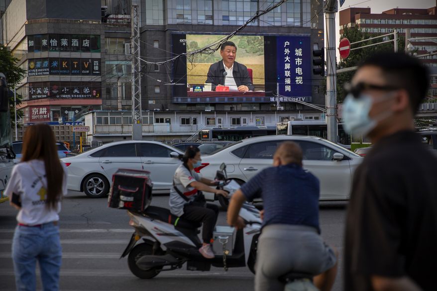 People wearing face masks to protect against the new coronavirus wait to cross an intersection as a large video screen shows Chinese President Xi Jinping speaking in Beijing, Tuesday, June 30, 2020. China approved a contentious national security law that will allow authorities to crack down on subversive and secessionist activity in Hong Kong, a move many see as Beijing&#39;s boldest yet to erase the legal firewall between the semi-autonomous territory and the mainland&#39;s authoritarian Communist Party system. (AP Photo/Mark Schiefelbein)