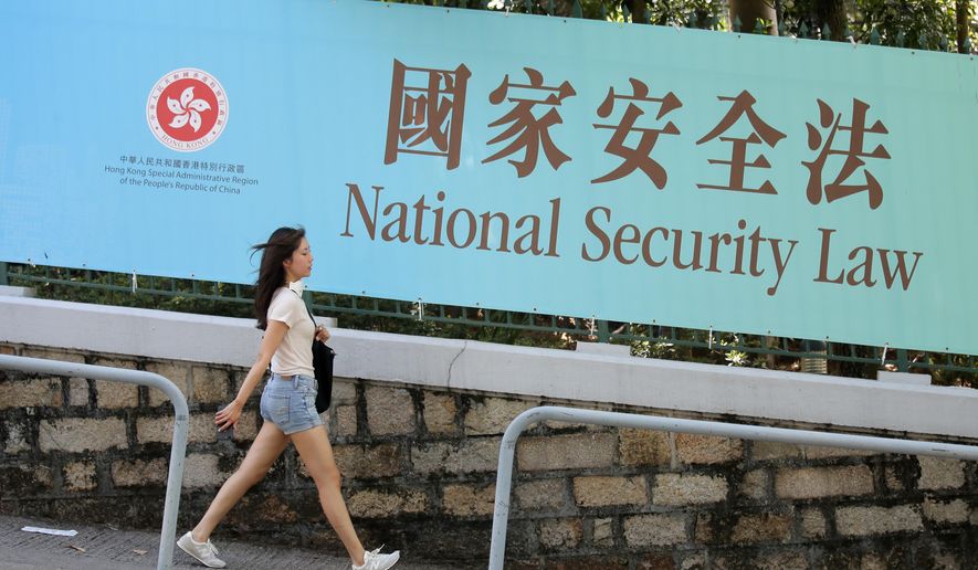 A woman walks past a promotional banner of the national security law for Hong Kong, in Hong Kong, Tuesday, June 30, 2020. China has approved a contentious law that would allow authorities to crack down on subversive and secessionist activity in Hong Kong, sparking fears that it would be used to curb opposition voices in the semi-autonomous territory. (AP Photo/Kin Cheung)