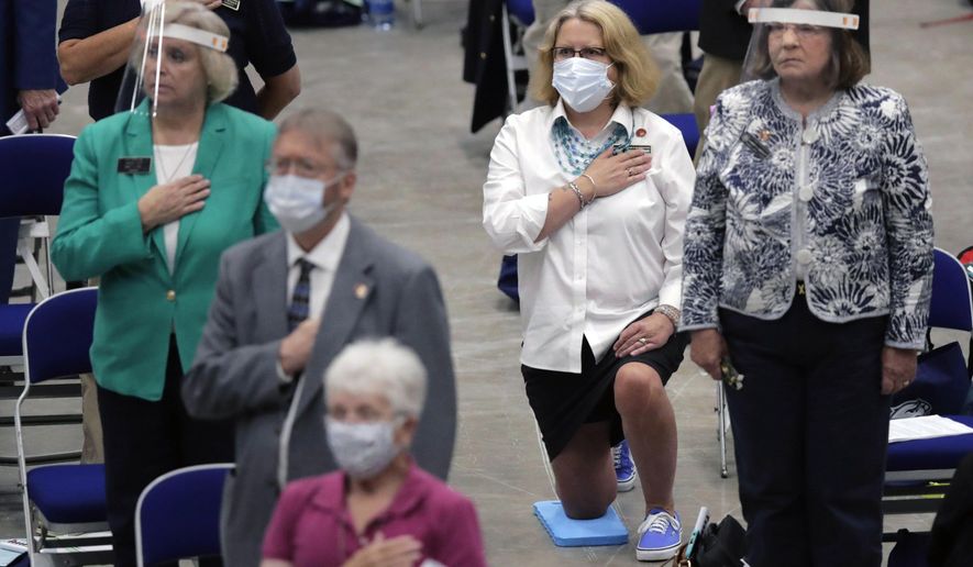 N.H. Rep. Wendy Thomas, D-Hillsborough Co., kneels for the national anthem during a legislative session on the drained hockey rink at the University of New Hampshire on Tuesday, June 30, 2020, in Durham, N.H. The N.H. House of Representatives met for their scheduled final session of the year, with safety restrictions due to the COVID-19 virus outbreak. (AP Photo/Charles Krupa)