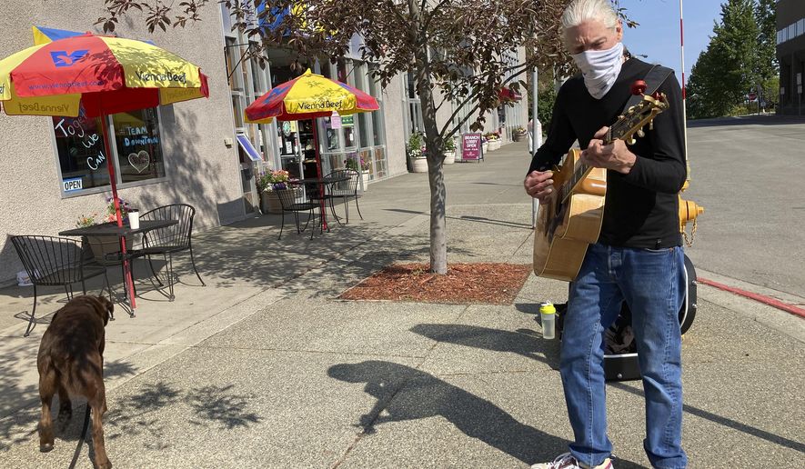 Street musician Cal Austermuhl performs on a street in downtown Anchorage, Alaska Wednesday, July 1, 2020, the same day Alaska residents began receiving their share of the state&#39;s oil wealth. Austermuhl says his $992 share was already spent on bills. (AP Photo/Mark Thiessen)
