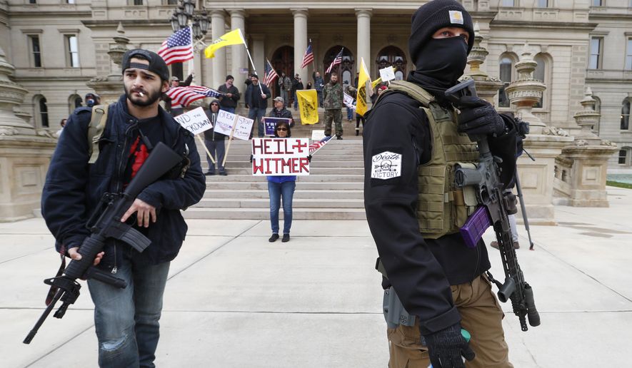 FILE - In this April 15, 2020, file photo protesters carry rifles near the steps of the Michigan State Capitol building in Lansing, Mich. A board overseeing Michigan's Capitol has determined it has the legal authority to decide if guns will continue to be allowed in the Lansing building and on its grounds. The Michigan State Capitol Commission on Tuesday, June 30, reviewed a formal legal opinion by Democratic Attorney General Dana Nessel that said the board had the power to prohibit firearms at the Capitol. (AP Photo/Paul Sancya, File)