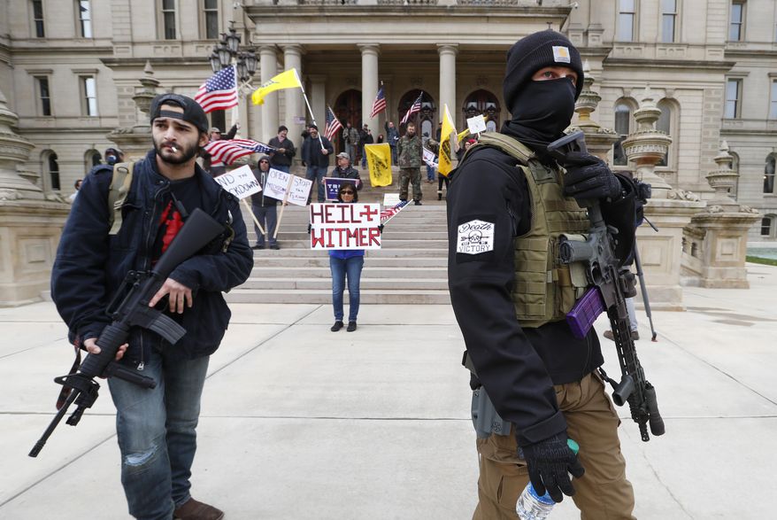 FILE - In this April 15, 2020, file photo protesters carry rifles near the steps of the Michigan State Capitol building in Lansing, Mich. A board overseeing Michigan's Capitol has determined it has the legal authority to decide if guns will continue to be allowed in the Lansing building and on its grounds. The Michigan State Capitol Commission on Tuesday, June 30, reviewed a formal legal opinion by Democratic Attorney General Dana Nessel that said the board had the power to prohibit firearms at the Capitol. (AP Photo/Paul Sancya, File)