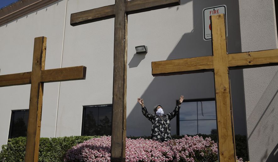 In this April 12, 2020, file photo, a woman prays while wearing a face mask before speaking at an Easter drive-in service at the International Church of Las Vegas, in Las Vegas. Nevada&#39;s lawyers say the 50-person cap the state has placed on worship services due to the coronavirus doesn&#39;t infringe on constitutional protections of religious freedom because it doesn&#39;t target anyone&#39;s ideology or opinion. (AP Photo/John Locher, File)