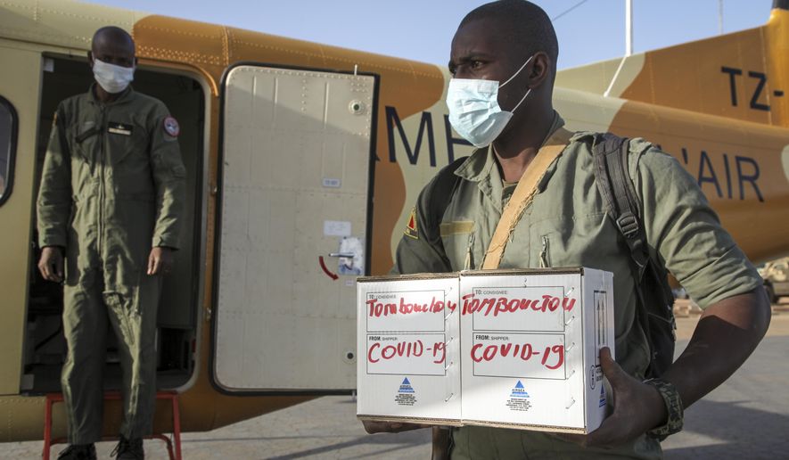 In this photo taken Friday, May 22, 2020, a Malian soldier in the capital Bamako, in Timbuktu, Mali, carries samples from patients in Timbuktu to a military plane flying them to be tested for the coronavirus. COVID-19 has made its way to Timbuktu, a town whose name has long been synonymous around the world with remoteness. (AP Photo/Baba Ahmed)