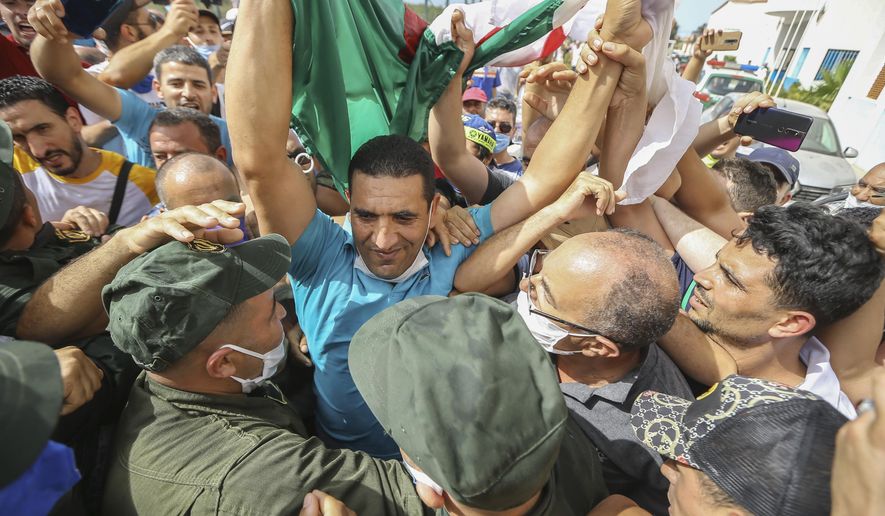 Activist Karim Tabbou holds a Algerian flag is greeted by supporters as he is released from the prison of Kolea, west of Algiers, Algeria, Thursday, July 2, 2020. Activists Karim Tabbou and Amira Bouraoui have been released from the prison of Kolea, west of Algiers, following decisions from Algerian courts. (AP Photo/Anis Belghoul)