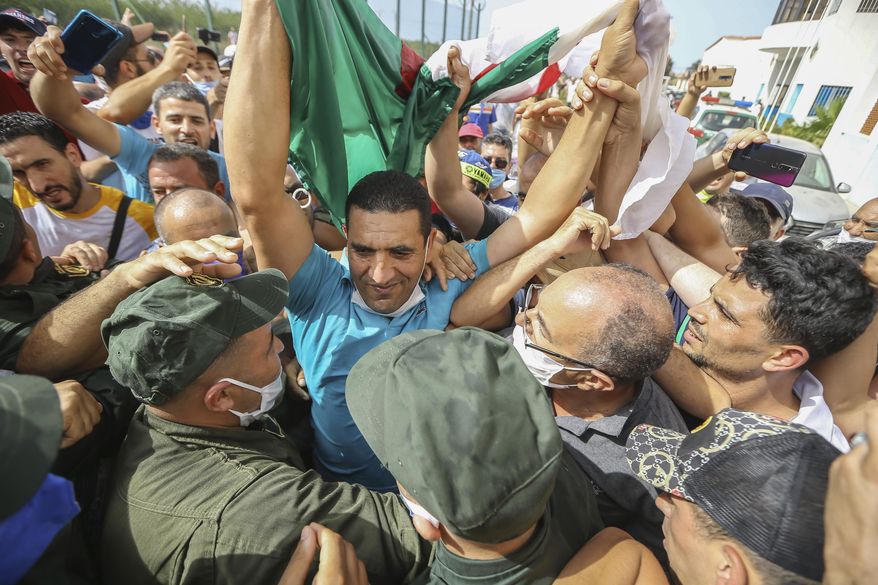 Activist Karim Tabbou holds a Algerian flag is greeted by supporters as he is released from the prison of Kolea, west of Algiers, Algeria, Thursday, July 2, 2020. Activists Karim Tabbou and Amira Bouraoui have been released from the prison of Kolea, west of Algiers, following decisions from Algerian courts. (AP Photo/Anis Belghoul)