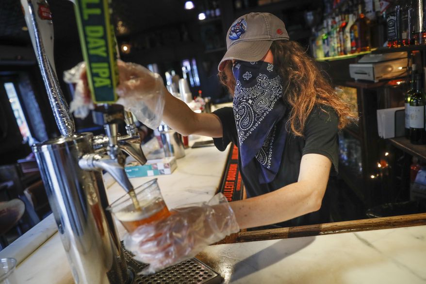 In this June 22, 2020, file photo, a bartender pours a beer for a customer at Shade Bar NYC in New York. Authorities are closing honky tonks, bars and other drinking establishments in some parts of the U.S. to stem the surge of COVID-19 infections — a move backed by sound science about risk factors that go beyond wearing or not wearing masks. (AP Photo/John Minchillo, File)
