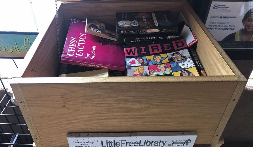 In this April 21, 2020, photo, a full little free library sits outside of a grocery store in Placitas, N.M. Across the United States, volunteers are reporting a jump in usages of official and unofficial tiny popups known as little free libraries as readers look to pass the time amid COVID-19 health restriction. From the American Southwest to New England, little free libraries made of wood or brick, placed in front of parks or in the trunk of a car, have seen their small spaces overwhelmed with books. (AP Photo/Russell Contreras)