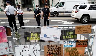 Police stand on the street beside a protest encampment surrounded by handmade signs and barricades outside City Hall, Friday, June 26, 2020, in New York. (AP Photo/John Minchillo)