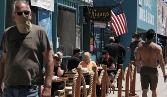 Restaurant patrons sit at an outside seating area as pedestrians pass by in the Venice beach area of Los Angeles on Friday, July 3, 2020. California took a big step back in reopening its economy as Gov. Gavin Newsom shut down bars, wineries, museums, movie theaters and inside restaurant dining across most of the state for three weeks amid troubling increases in coronavirus cases and hospitalizations. (AP Photo/Richard Vogel)