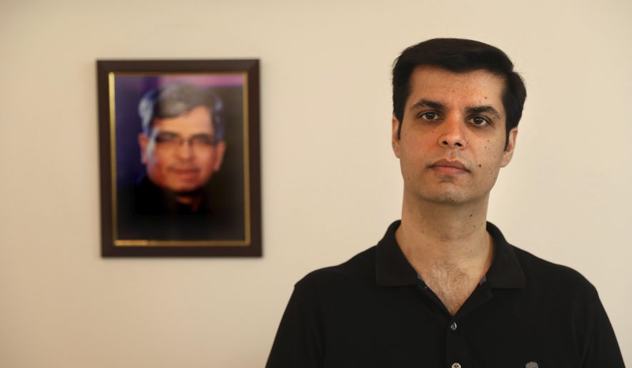 Karan Murgai, an IT management consultant for a multinational based in Dallas, poses for a photograph next to then portrait of his father Satish Murgai, in his Delhi house, in New Delhi, India, Tuesday, June 30, 2020. Murgai came to Delhi in March this year after his father died. Murgai and at least 1,000 others like him, whose U.S. visas are tied to their jobs in the U.S., are now stranded in India, after an executive order signed by President Donald Trump that suspends applications for H-1B and other high-skilled work visas from abroad. (AP Photo/Manish Swarup)