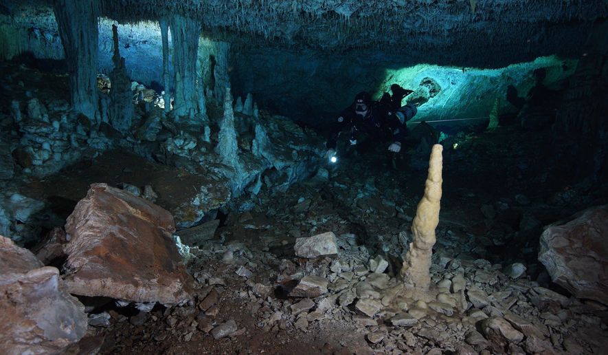 This Dec. 12, 2019 photo released by CINDAQ.ORG, or "Centro Investigador del Sistema Acuífero de Quintana Roo," shows a diver in the "La Mina Roja" passage of the Sagitario underwater cave system near Playa del Carmen in Mexico's Yucatan Peninsula. The discovery of remains of human-set fires, stacked mining debris, simple stone tools, navigational aids, and digging sites suggest humans went into the caves around 12,000 to 14,000 years ago, seeking iron-rich red ocher, which early peoples in the Americas prized for decoration and rituals. (CINDAQ.ORG via AP)