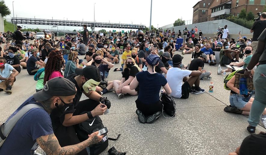 Protesters sit on Interstate 64 in St. Louis for several moments, Friday, July 3, 2020, in memory of George Floyd. The protest, the latest organized by the group Expect Us, was among several protests in the weeks since Floyd's death in Minneapolis reopened long-standing concerns about police treatment of Black people in the United States. Police closed the interstate to traffic in both directions and allowed the protesters to walk onto the highway. (AP Photo/Jim Salter)
