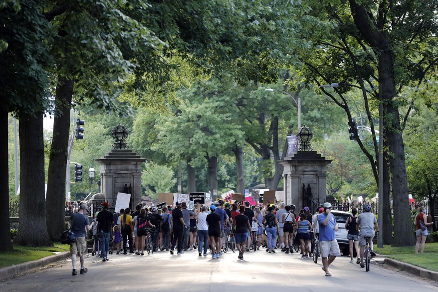 Protesters walk through the gate of a private street not far from the home of Mark and Patricia McCloskey, Friday, July 3, 2020, in St. Louis. Mark and Patricia McCloskey were seen on June 28, 2020, standing outside their mansion with guns drawn confronting passing protesters. The protesters passed by the home again on Friday evening without incident. (AP Photo/Jeff Roberson)
