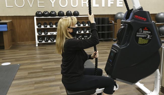 FILE - In this Thursday, July 2, 2020, file photo, Jennifer Sposato, a trainer at Life Time health club, works out as the club remains open even as Arizona Gov. Doug Ducey has issued an executive order for all gyms to close due to the surge in coronavirus cases in Phoenix, Ariz. Life Time health club, one of two health club chains in Arizona that had defied a state order to shut down and faced possible legal action said Friday, July 2, 2020, it had closed. Life Time Fitness informed state officials of its decision after getting a letter on Thursday threatening legal action by the state. (AP Photo/Ross D. Franklin, File)