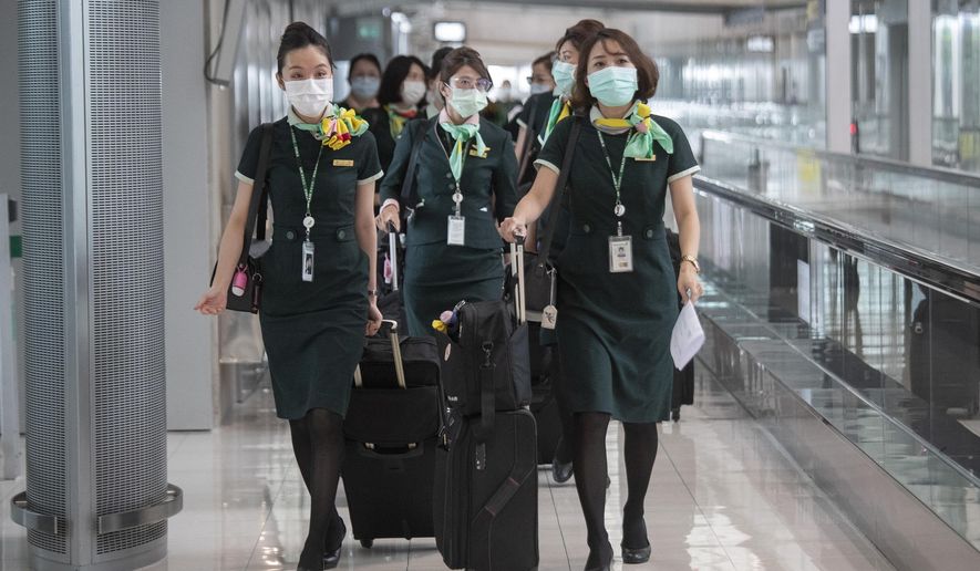 Flight crew wear protective masks as they arrive at the Suvarnabhumi Airport in Bangkok, Friday, July 3, 2020. As the country starts to ease its travel restrictions allowing foreign visitors in on a controlled basis, a laboratory at the airport will have the results of COVID-19 virus testing ready within 90 minutes for arriving travelers. (AP Photo/Sakchai Lalit)