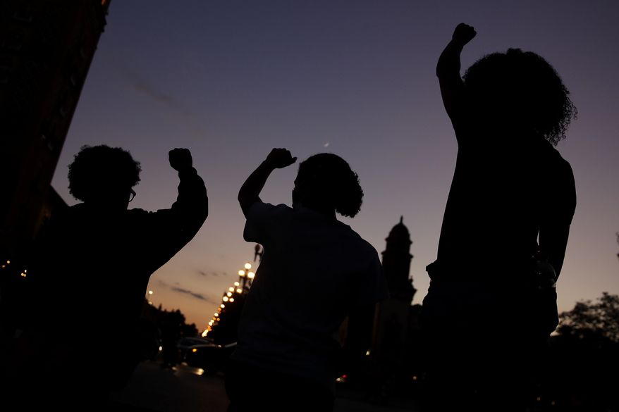 In this June 23, 2020, file photo, people raise their fists in Kansas City, Mo., during a protest over the death of Black people at the hands of police. (AP Photo/Charlie Riedel) **FILE**