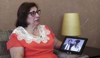 Laure Ghosn, whose husband Charbel Zogheib has been missing for the past 37 years, speaks as she holds their wedding portrait during an interview at her home in Sarba, north of Beirut, Lebanon. Ghosn said her husband is held in Syria and hopes that a new wave of sanctions imposed by the U.S. against the Syrian government will force Damascus to reveal the fate of hundreds of Lebanese citizens held in Syria, including that of her husband. (AP Photo/Bilal Hussein)