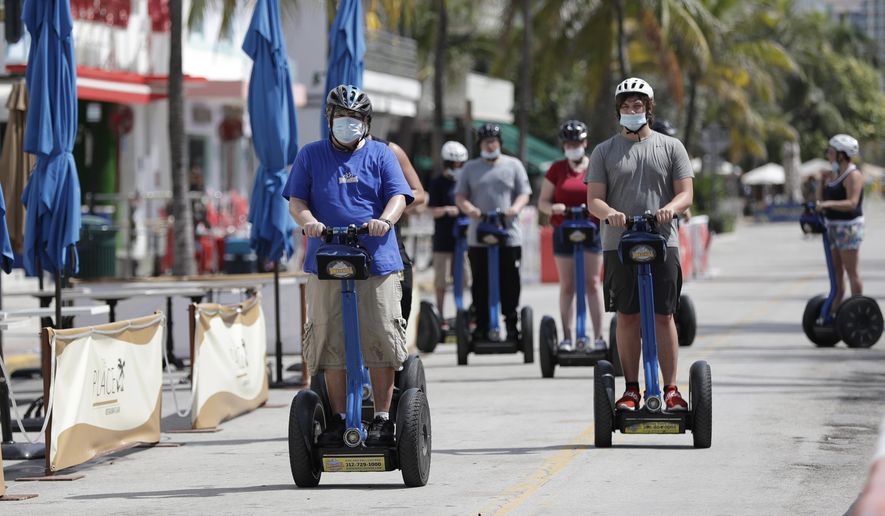 A tour group riding Segways rides down Miami Beach, Florida&#39;s famed Ocean Drive on South Beach, July 4, 2020. The Fourth of July holiday weekend began Saturday with some sobering numbers in the Sunshine State: Florida logged a record number of people testing positive for the coronavirus. (AP Photo/Wilfredo Lee)