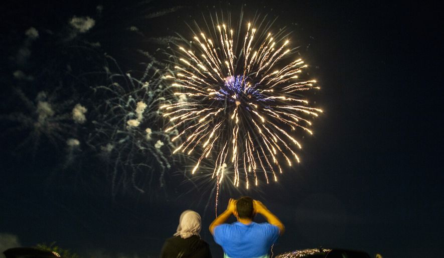 A family takes photos as fireworks explode during the Coralville 4th Fest drive-in fireworks show amid the novel coronavirus pandemic, Saturday, July 4, 2020, in Coralville, Iowa. (Joseph Cress/Iowa City Press-Citizen via AP)