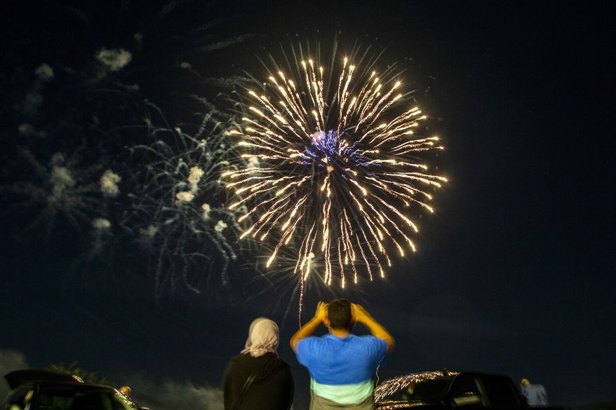 A family takes photos as fireworks explode during the Coralville 4th Fest drive-in fireworks show amid the novel coronavirus pandemic, Saturday, July 4, 2020, in Coralville, Iowa. (Joseph Cress/Iowa City Press-Citizen via AP)