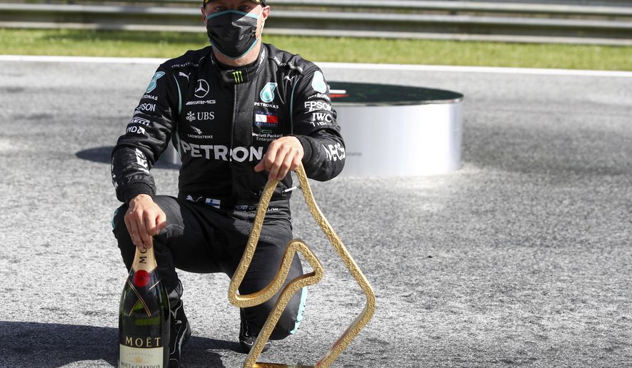 Mercedes driver Valtteri Bottas of Finland poses with his trophy and a bottle of champagne after winning the Austrian Formula One Grand Prix at the Red Bull Ring racetrack in Spielberg, Austria, Sunday, July 5, 2020. (Mark Thompson/Pool via AP)