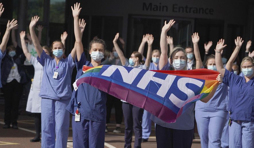NHS staff outside Royal Victoria Infirmary join in the pause for applause to salute the NHS 72nd birthday, in Newcastle, England, Sunday, July 5, 2020. People across the U.K. joined a round of applause to celebrate the 72nd anniversary of the formation of the free-to-use National Health Service, undoubtedly the country’s most cherished institution. The reverence with which it is held has been accentuated this year during the coronavirus pandemic. (Owen Humphreys/PA via AP)