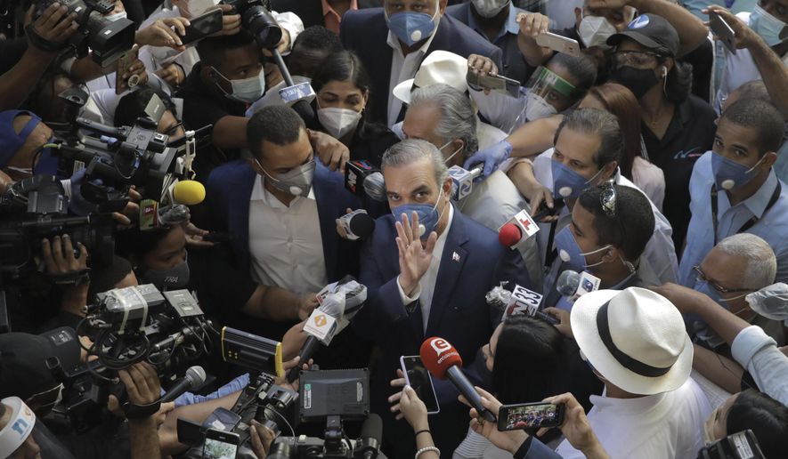 Luis Abinader, presidential candidate of the opposition Modern Revolutionary Party, greets the crowd while he is surrounded by journalists at a voting center during the presidential elections, in Santo Domingo, Dominican Republic, Sunday, July 5, 2020. (AP Photo/Tatiana Fernandez)